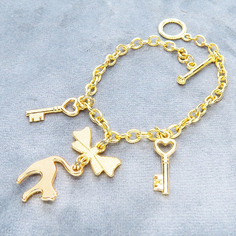 マットゴールドの跳ね猫シルエットモチーフとリボンに鍵が連なるブレスレット