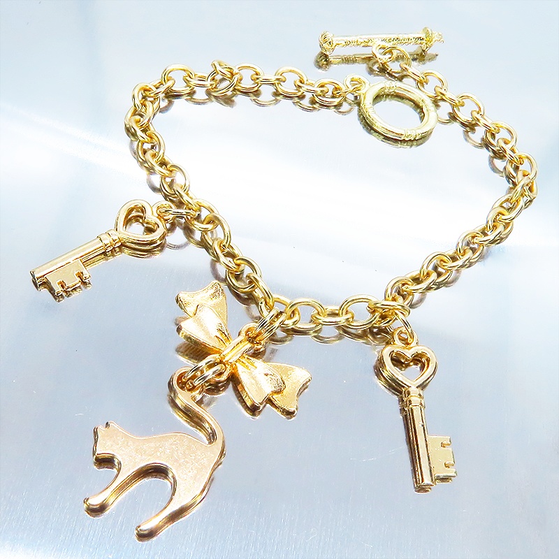 マットゴールドの跳ね猫シルエットモチーフとリボンに鍵が連なるブレスレット