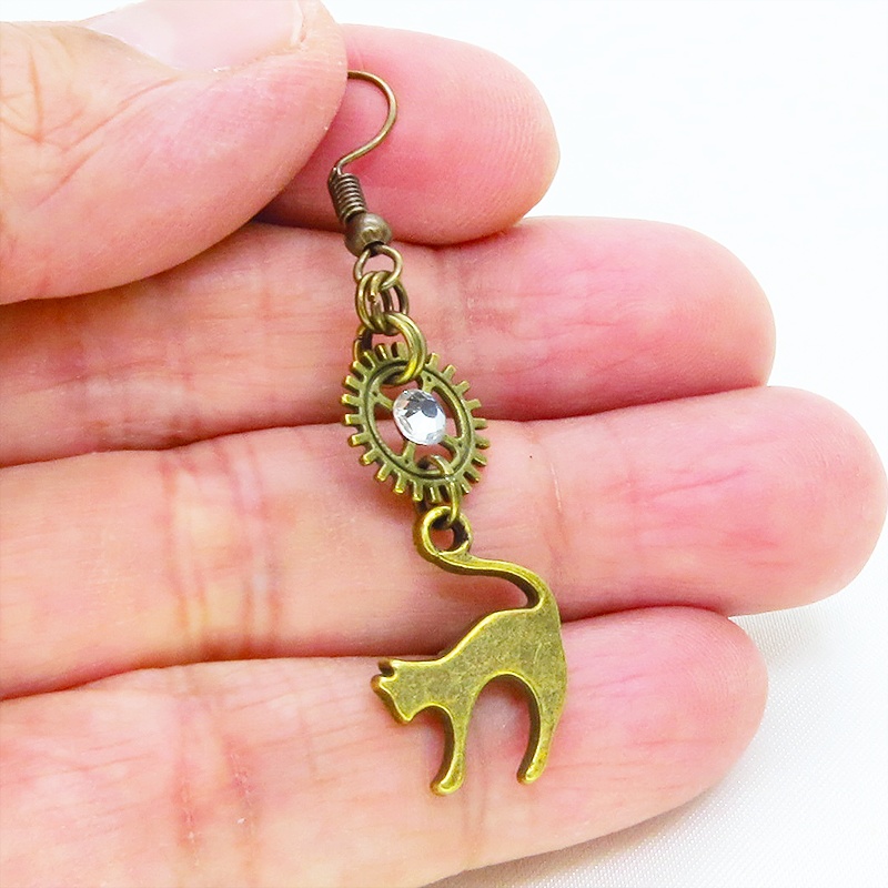 アンティークゴールド 跳ね猫モチーフと歯車を組合せたシンプルなピアス クリスタルガラス