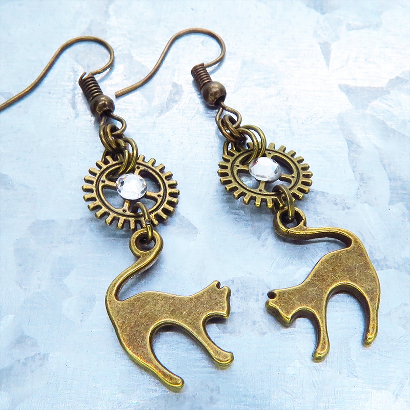アンティークゴールド 跳ね猫モチーフと歯車を組合せたシンプルなピアス クリスタルガラス