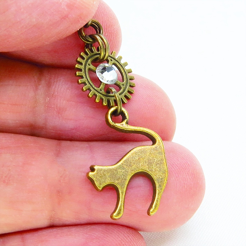 アンティークゴールド 跳ね猫モチーフと歯車を組合せたシンプルなピアス クリスタルガラス