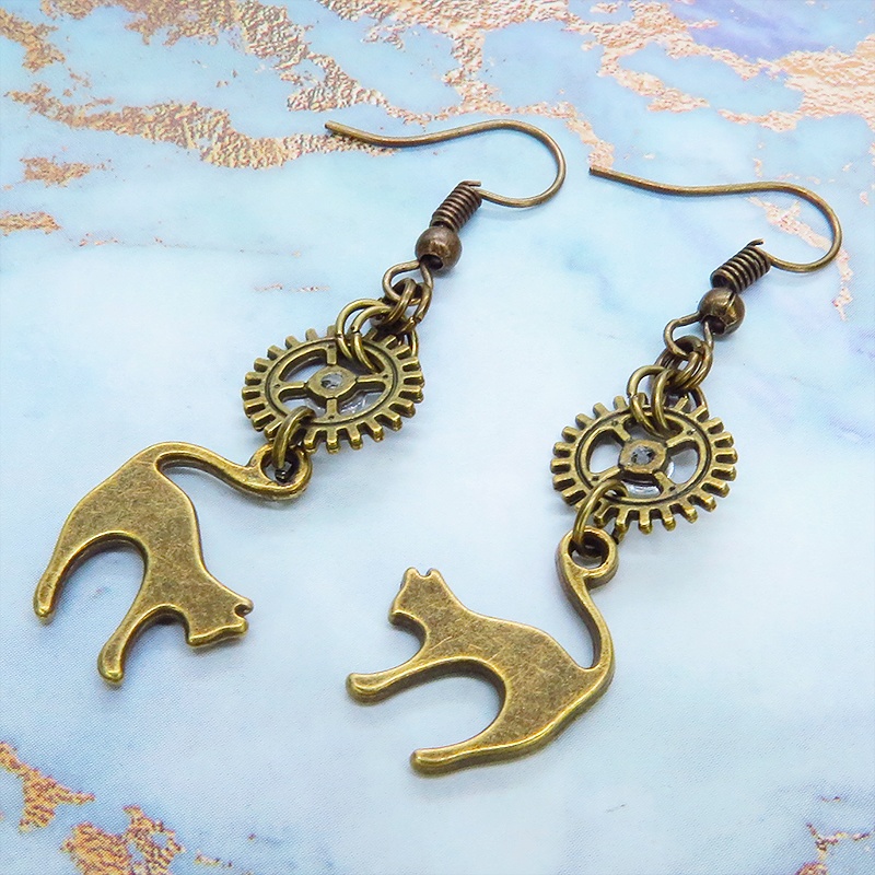 アンティークゴールド 跳ね猫モチーフと歯車を組合せたシンプルなピアス クリスタルガラス