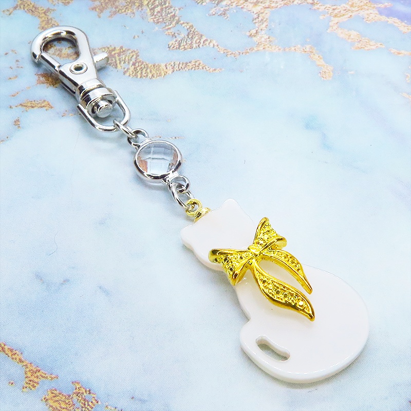 ゴールドカラーリボン付きの白猫シルエットモチーフとラインストーンのキーホルダー 金具変更可