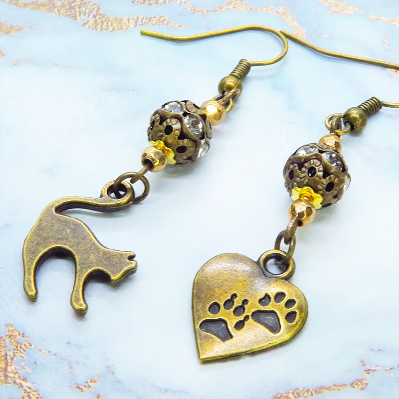 アンティークゴールド 跳ね猫と肉球ハートと組合せたアシンメトリーピアス メタルビーズ ラインストーン