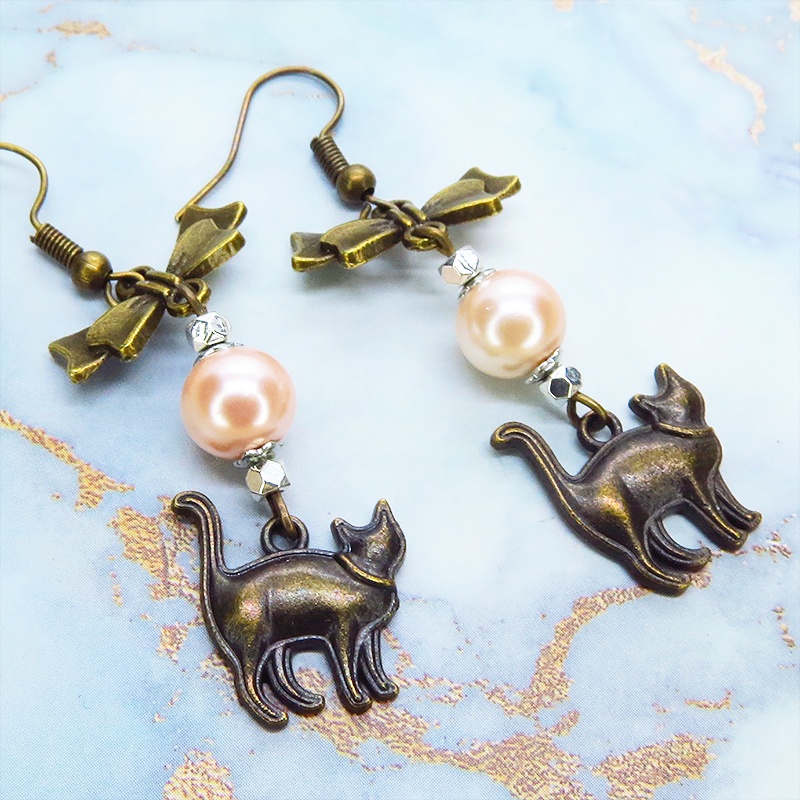 アンティークゴールド 歩き猫とリボンにベージュカラーのビーズを組合せた大人可愛いピアス サージカル可