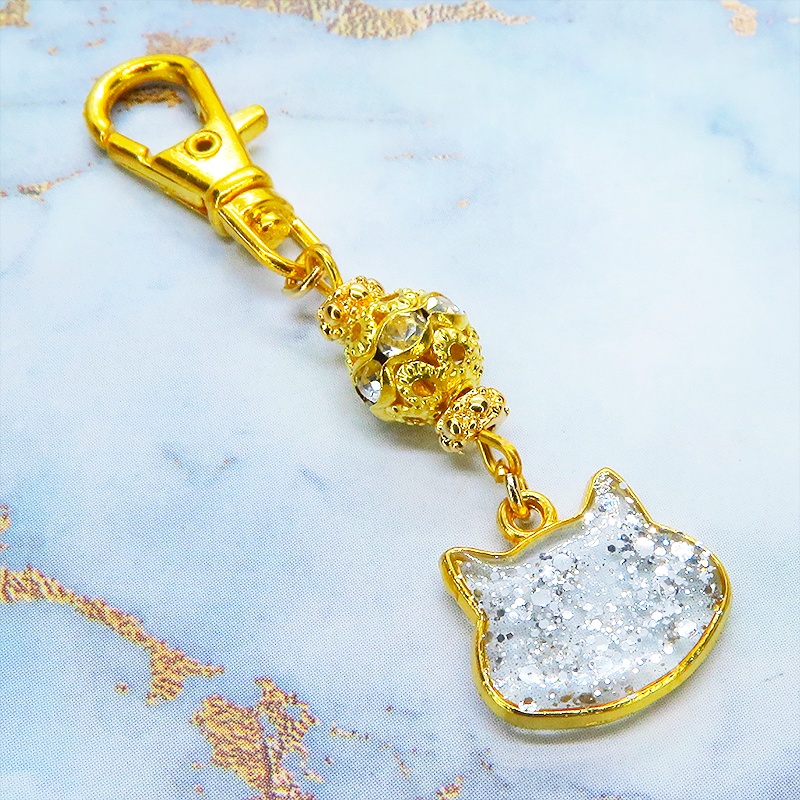 ゴールドカラー 猫フェイスモチーフのクリアカラーレジンのキーホルダー ラインストーン入りメタルビーズ 金具変更可