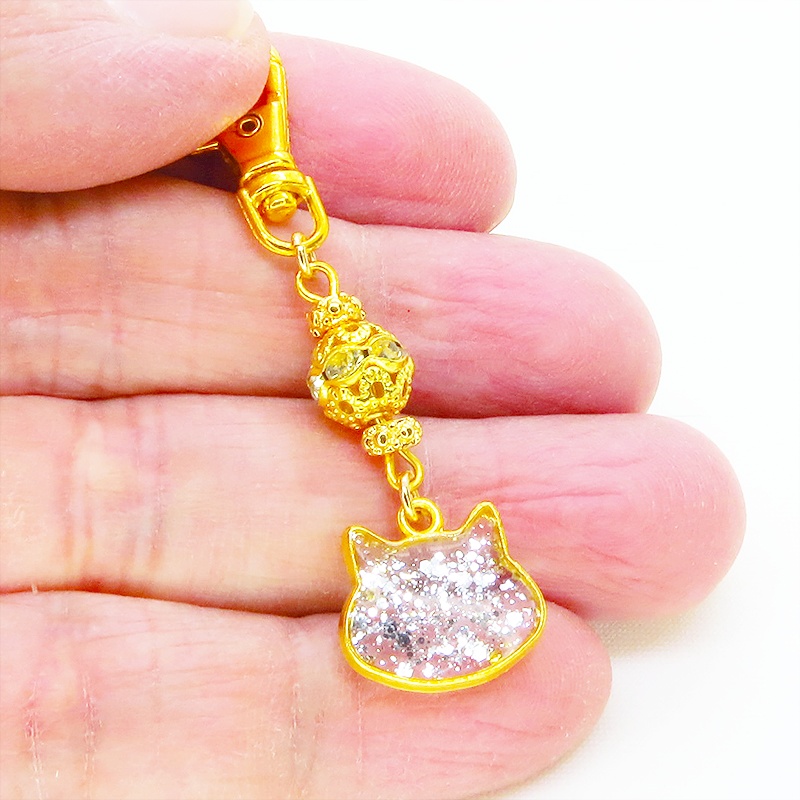 ゴールドカラー 猫フェイスモチーフのクリアカラーレジンのキーホルダー ラインストーン入りメタルビーズ 金具変更可
