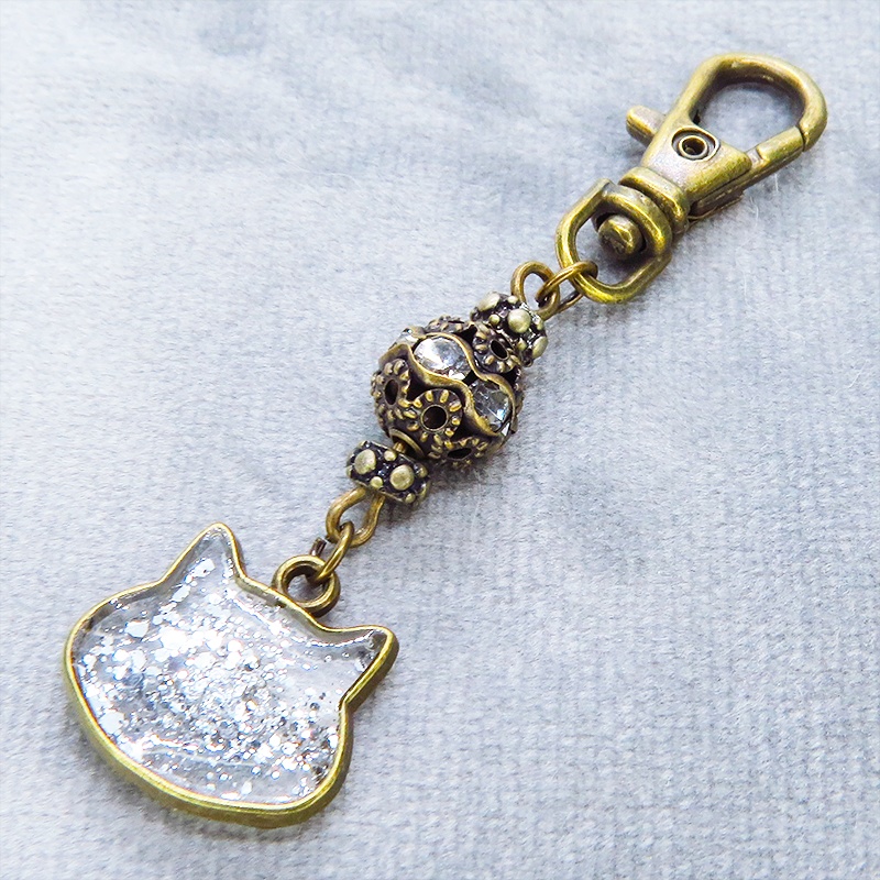 アンティークゴールド 猫フェイスモチーフのクリアカラーレジンのキーホルダー ラインストーン入りメタルビーズ 金具変更可
