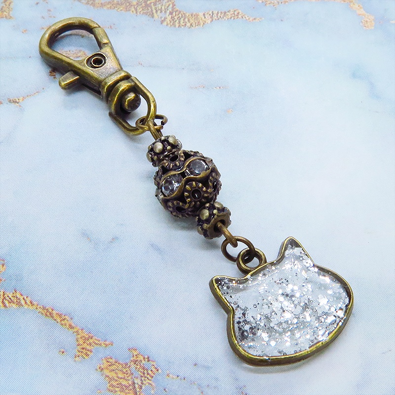 アンティークゴールド 猫フェイスモチーフのクリアカラーレジンのキーホルダー ラインストーン入りメタルビーズ 金具変更可