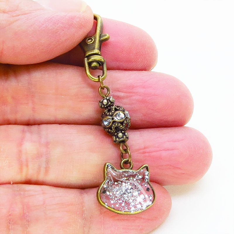 アンティークゴールド 猫フェイスモチーフのクリアカラーレジンのキーホルダー ラインストーン入りメタルビーズ 金具変更可