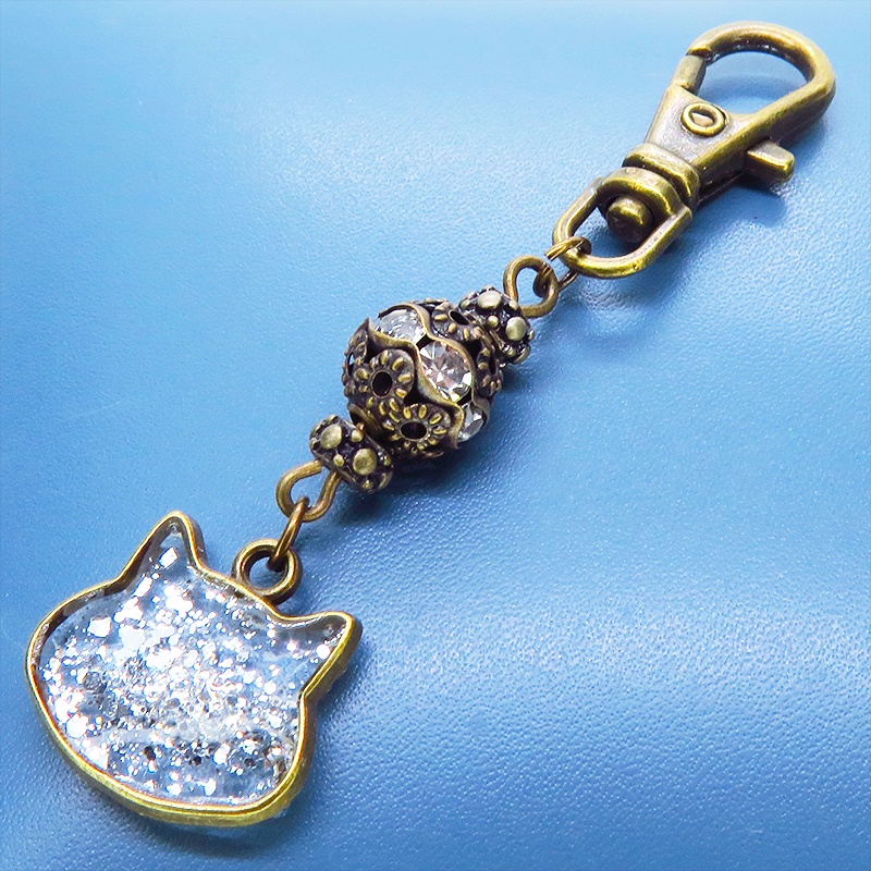 アンティークゴールド 猫フェイスモチーフのクリアカラーレジンのキーホルダー ラインストーン入りメタルビーズ 金具変更可