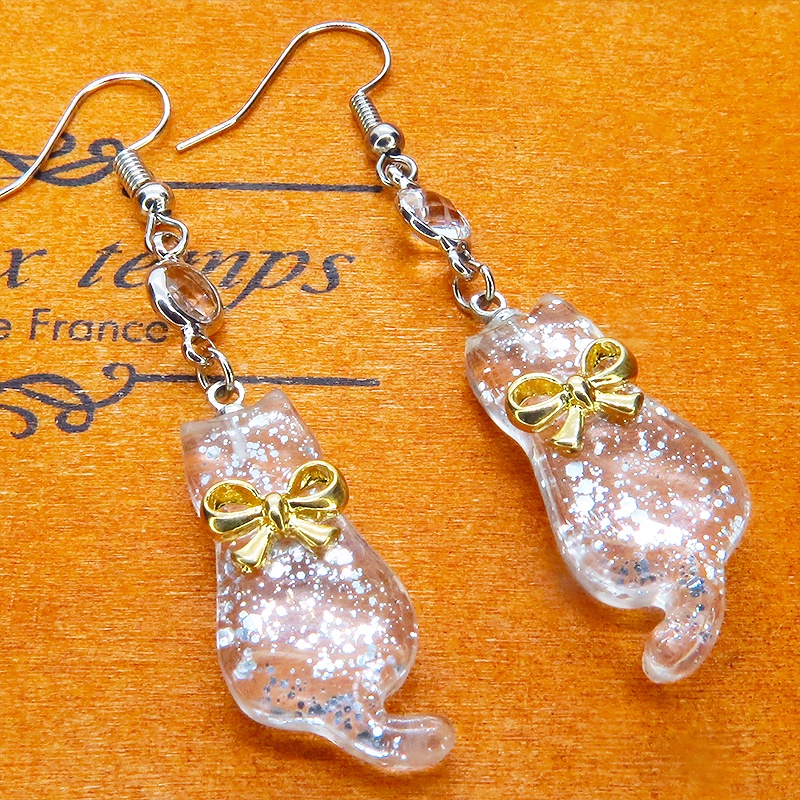 ゴールドカラーのリボンを付けたクリアカラーの猫シルエットモチーフのピアス ラインストーン サージカル可