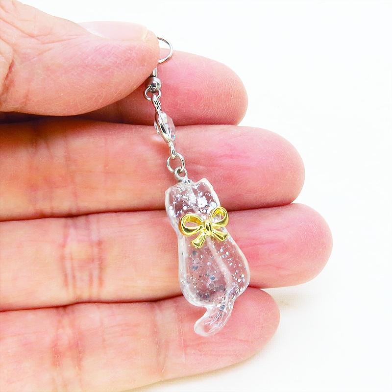 ゴールドカラーのリボンを付けたクリアカラーの猫シルエットモチーフのピアス ラインストーン サージカル可