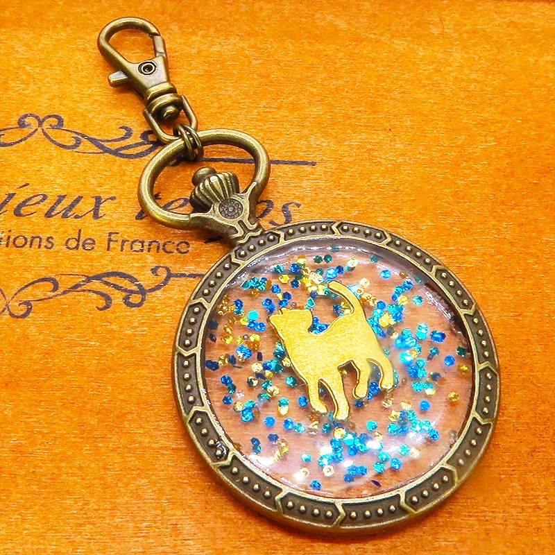 アンティークゴールド ゴールドカラーの振り向き猫の懐中時計型のキーホルダー 金具変更可