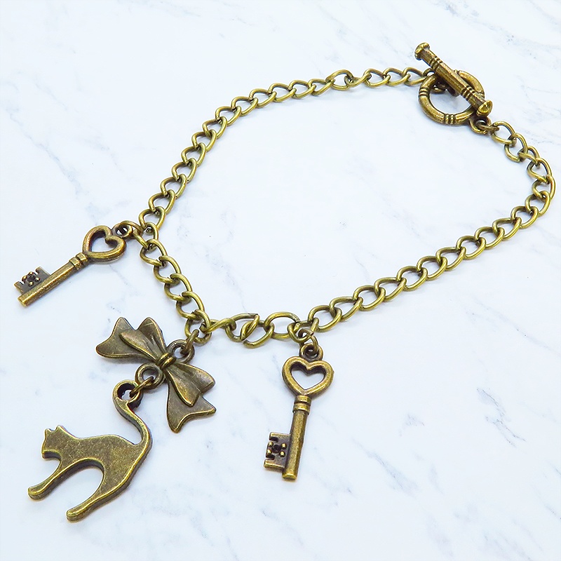 アンティークゴールド 跳ね猫シルエットモチーフとリボンに鍵が連なる大人可愛いブレスレット