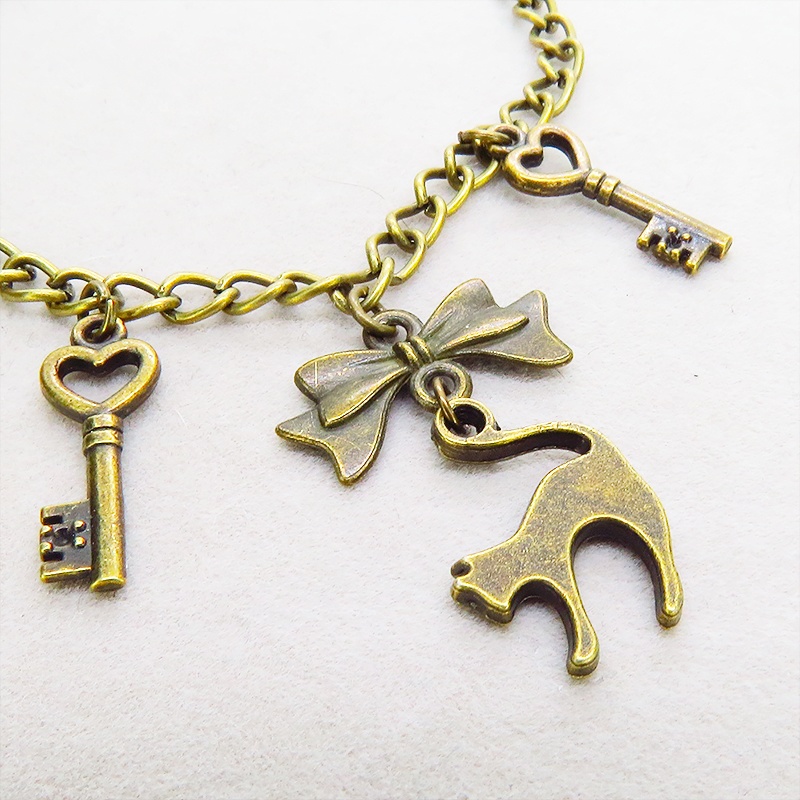 アンティークゴールド 跳ね猫シルエットモチーフとリボンに鍵が連なる大人可愛いブレスレット