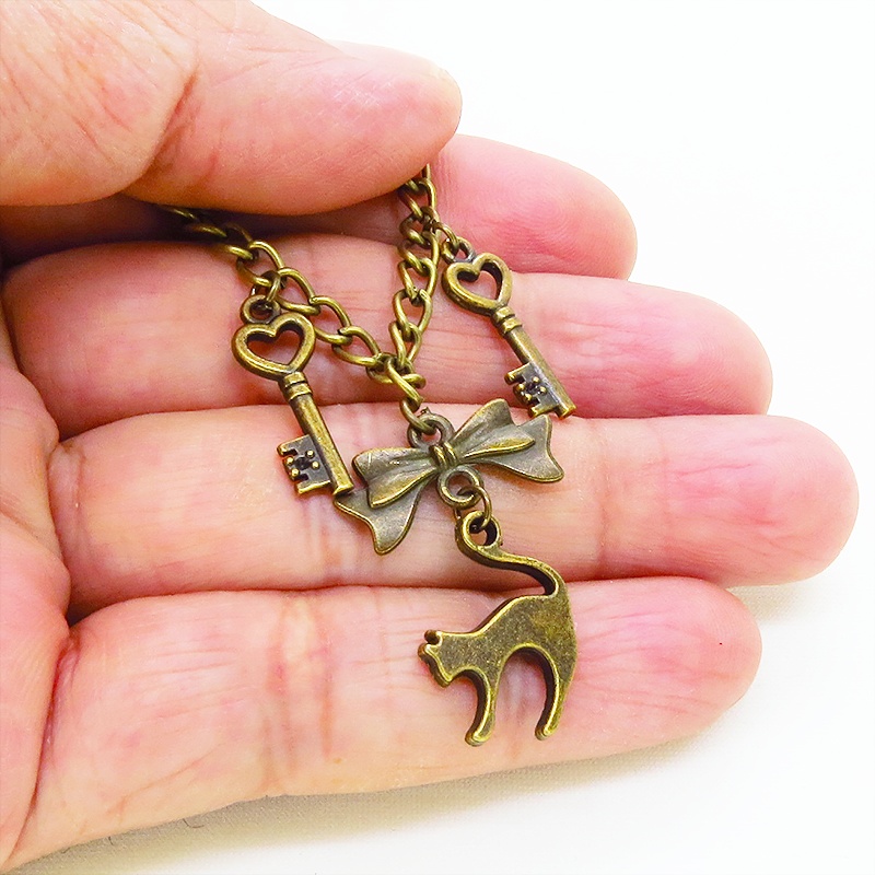 アンティークゴールド 跳ね猫シルエットモチーフとリボンに鍵が連なる大人可愛いブレスレット