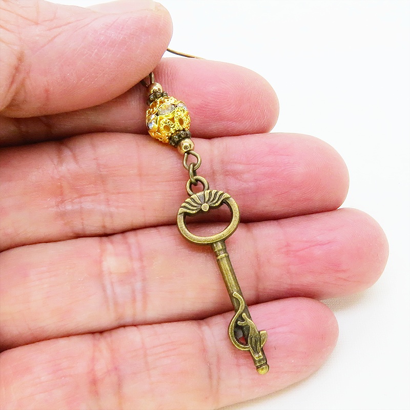 アンティークゴールド 猫が座る鍵モチーフのロングピアス ゴールドメタルビーズ ラインストーン