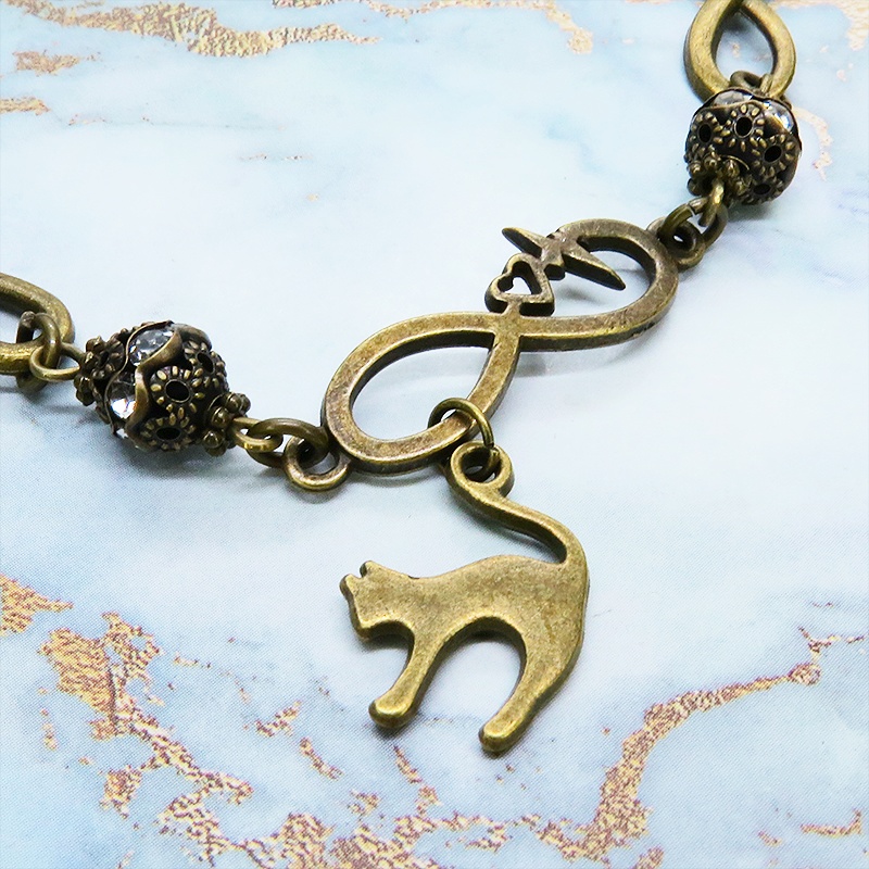 アンティークゴールド 跳ね猫モチーフのブレスレット ラインストーンとエターナルモチーフのチェーン