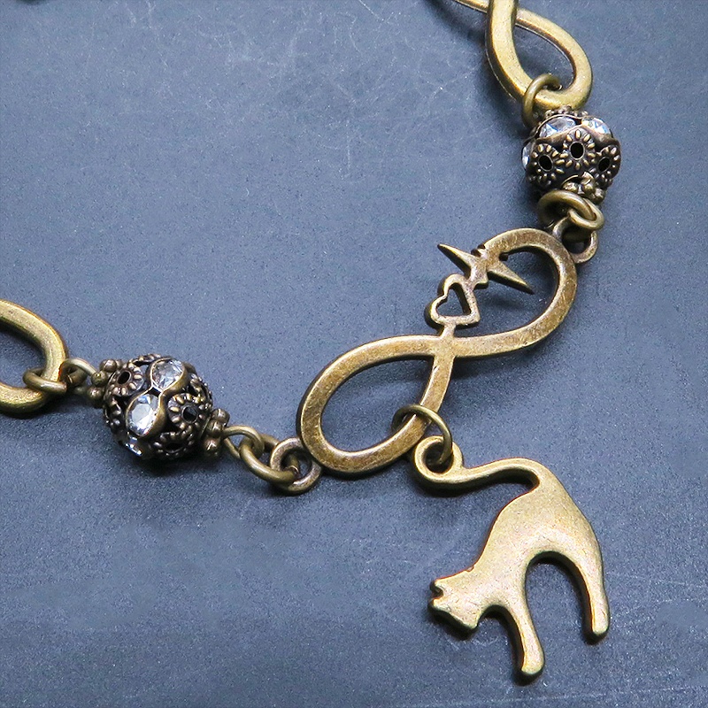 アンティークゴールド 跳ね猫モチーフのブレスレット ラインストーンとエターナルモチーフのチェーン