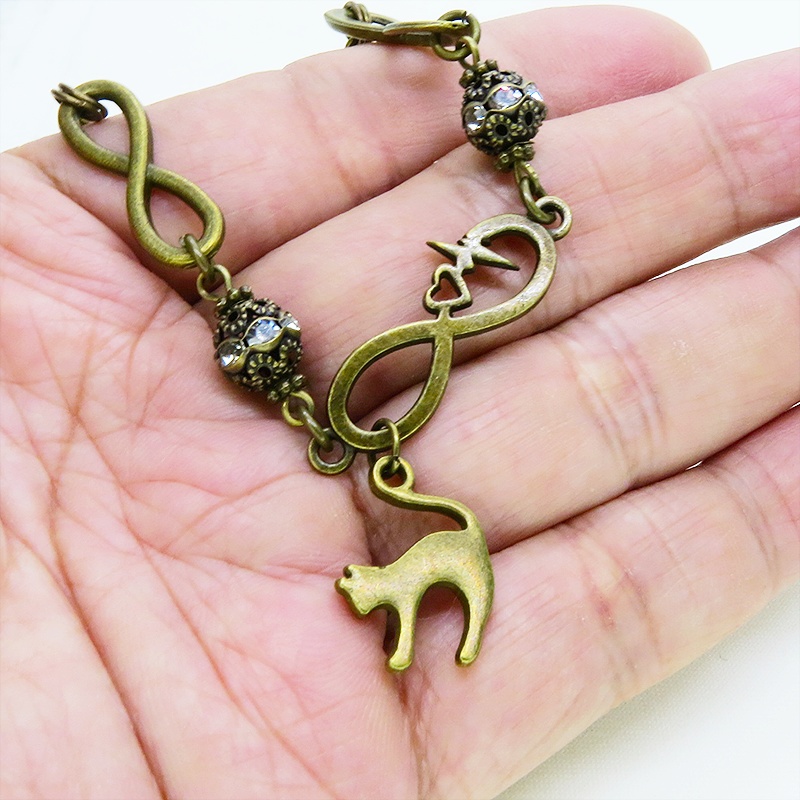 アンティークゴールド 跳ね猫モチーフのブレスレット ラインストーンとエターナルモチーフのチェーン