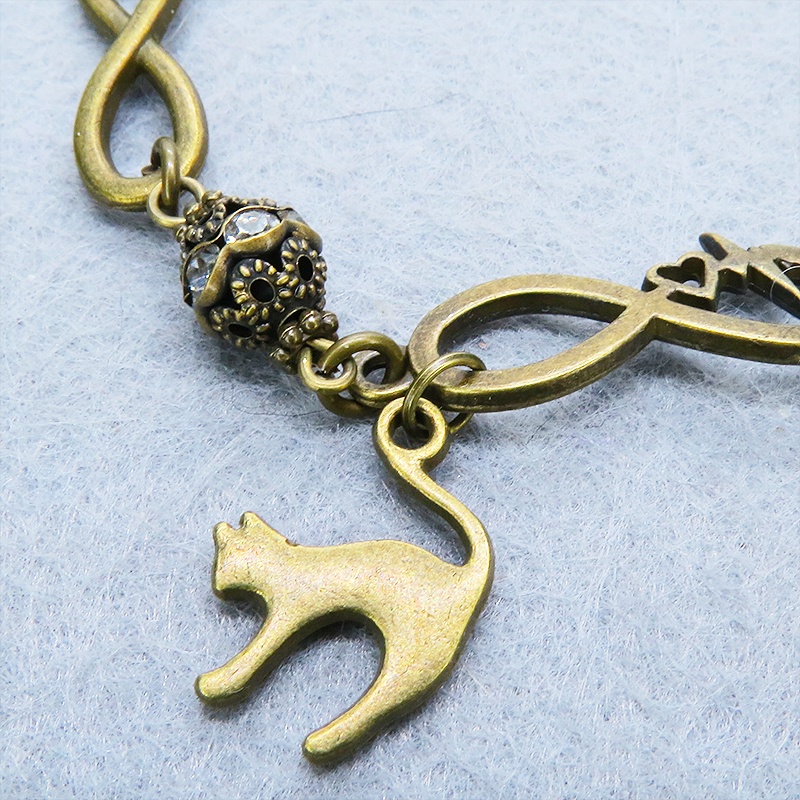 アンティークゴールド 跳ね猫モチーフのブレスレット ラインストーンとエターナルモチーフのチェーン