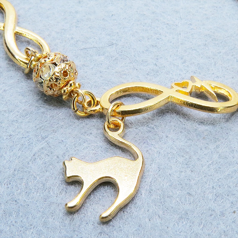 マットゴールド 跳ね猫モチーフのブレスレット ラインストーンとエターナルモチーフのチェーン