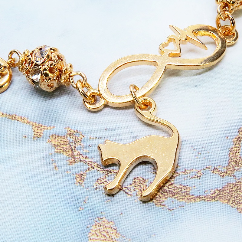 マットゴールド 跳ね猫モチーフのブレスレット ラインストーンとエターナルモチーフのチェーン