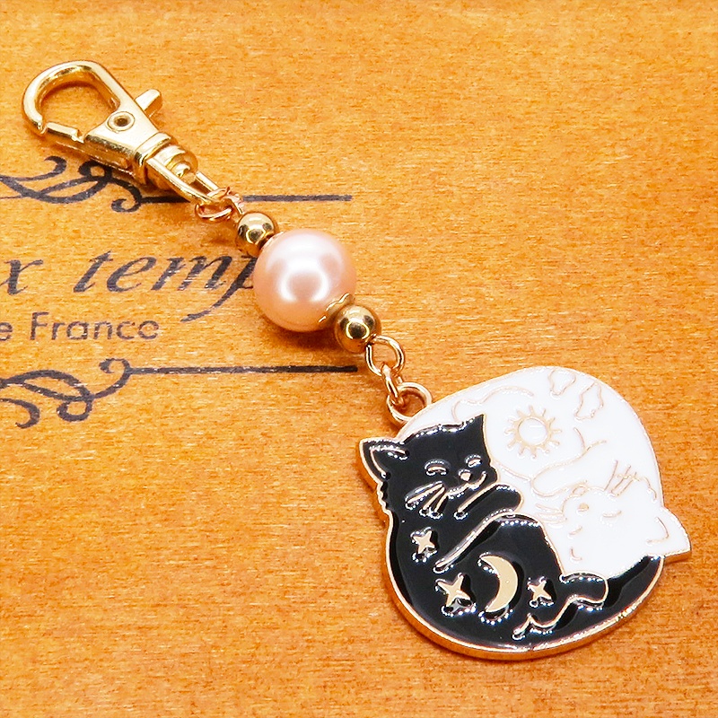 マットゴールド 白猫黒猫丸まってお休みチャームとコーラルピンクビーズのキーホルダー 金具変更可