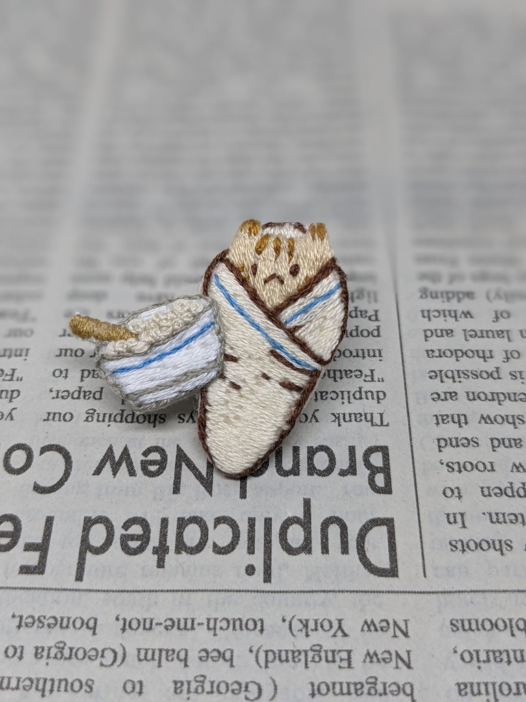 おくるみされる猫の刺しゅうブローチ