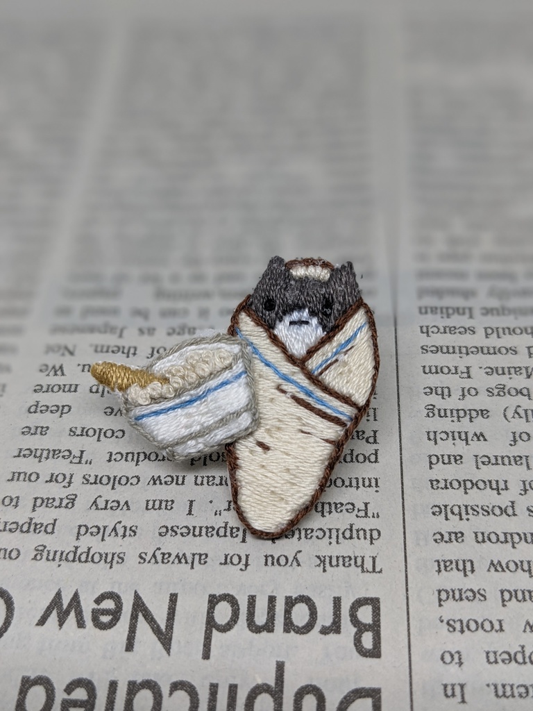 おくるみされる猫の刺しゅうブローチ