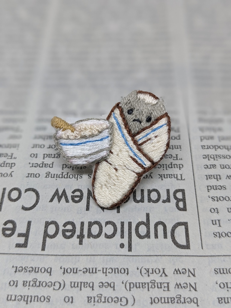 おくるみされる猫の刺しゅうブローチ