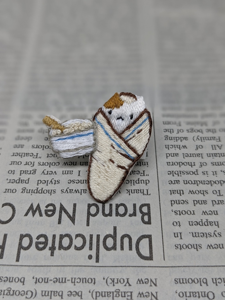 おくるみされる猫の刺しゅうブローチ